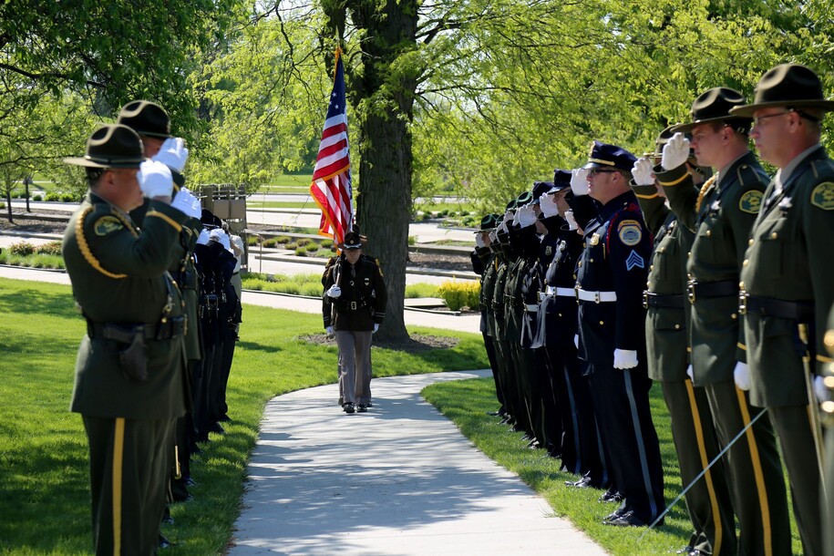 Lines of officers as honor guard and officer in the middle holding a flag